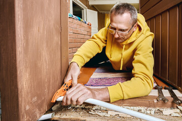 Plumber trims plastic pipe using cutting tool to ensure proper connection surface for placing...