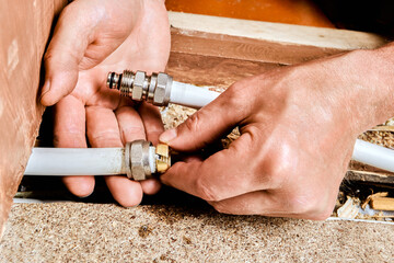 Compression ring is being positioned onto end of multilayer pipe by plumber preparing connection using metal fitting for domestic plumbing line.