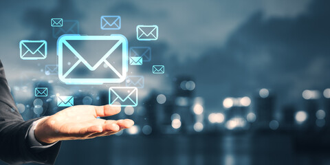 Businessman hand showing floating digital email icons on blurred city background symbolizing online communication and messaging technology concept.