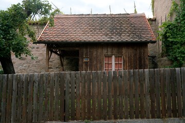 Holzschuppen mit Biberschwanzdach vor mittelalterlicher Mauer