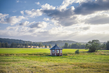 Small red building in a field with mountains in the background