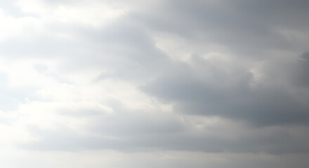 Obraz premium A soft, diffused light filters through a sky filled with clouds, creating a dreamlike atmosphere