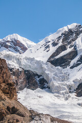 A breathtaking vertical view of a massive glacier flowing down a valley from majestic snowcapped mountain peaks under a clear sky