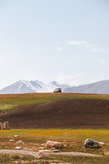 A white off-road vehicle sits on a remote hill in a scenic mountain landscape with majestic...
