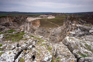 Fototapeta premium A wide-angle view of a rocky landscape with a large quarry in the background, perfect for design projects on geology, industrial themes, or a raw, rugged natural environment