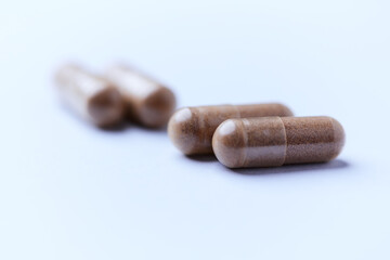 Ashwagandha (Withania somnifera) capsules. Concept for a healthy dietary supplementation. Bright paper background. Close up. Copy space.	