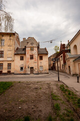 Weathered historic building with peeling facade on a quiet cobblestone street - ideal for urban heritage studies, architectural restoration visuals, and historical cityscape design references.