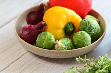 Close-up view of fresh colorful vegetables including bright bell pepper, red onion, and Brussels sprouts.