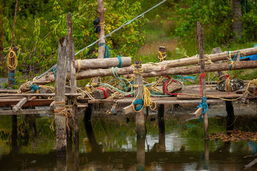 Fototapeta premium Hand-built wooden pier with ropes and rocks in a shallow river, a rustic and textured image for designers needing authentic, natural, or travel-themed visuals for a blog, website, or social media post