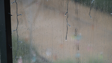 Rainy window with string lights and condensation