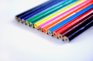 Bottom perspective view of colored pencils, arranged in order, diagonally, right side, on a white background