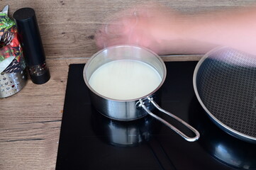 Cooking polenta porridge — a pot of milk heating on the stove while a cook sprinkles dry polenta into it.