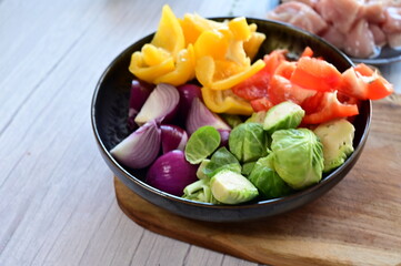 Top-down view of a bowl filled with freshly chopped vegetables, set against the background of meal...