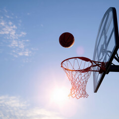Basketball soaring through the air towards the hoop during sunset with vibrant sky background