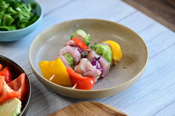 Close-up view of a raw chicken skewer prepared for roasting. Fresh pieces of chicken meat threaded onto a wooden stick along with colorful vegetables, creating an appetizing composition on a kitchen