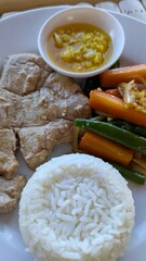 Closeup of fresh tuna steak, roasted vegetables, and white rice at Balinese warung restaurant in Bali Indonesia 