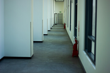 A long, empty, and modern hallway in a school building, with red fire extinguishers. Concept of safety and architecture