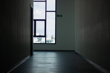 A dark hallway leading to a large, bright window. Concept of hope, escape, and the future