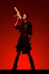 Female model in a sleek outfit wielding a toy weapon.