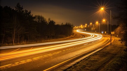 A winding road illuminated by streetlights at night, showcasing light trails from passing vehicles amidst a serene, dark landscape.