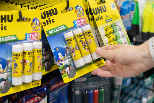 Poznan, Poland - July 24, 2025: A hand holds UHU Stic glue sticks, Sonic The Hedgehog packaging, on a store shelf, promoting children's popular stationery