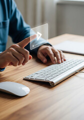 Person's hand touching transparent play button icon on wooden desk with keyboard and mouse