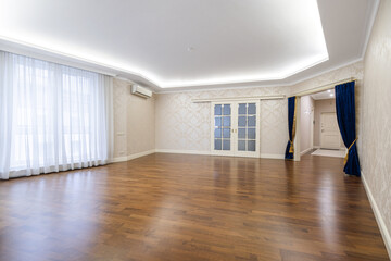 Bright and airy living room features large windows allowing natural light. Elegant design with wooden flooring and soft furnishings enhances the inviting atmosphere.