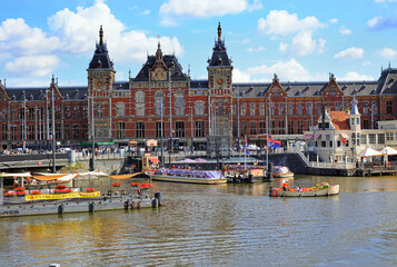  Amsterdam Central Station located very close to the River Amstel in the City Centre. There are many tourist boats eager to take tourists on a trip around the canals.