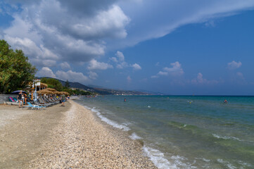 Paralia Alikes Beach in Zakynthos, Greece – Serene Shoreline with Sun Loungers and Mountain Views