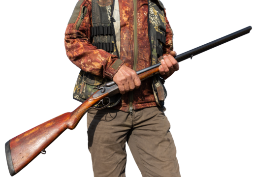 Mature man hunter with gun while walking on field.