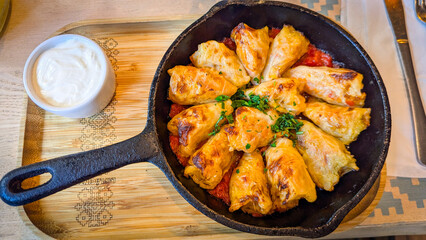 Traditional Stuffed Cabbage Rolls in Cast Iron Skillet. Baked cabbage rolls with meat and rice served in a cast iron skillet with tomato sauce and sour cream on the side.