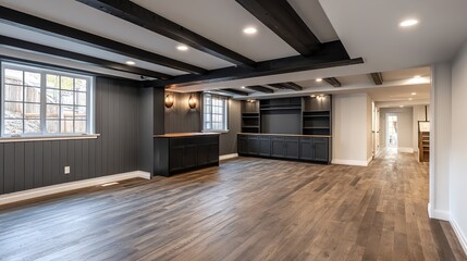 Stylish basement transformation featuring dark wood accents, beams, cabinets and warm hardwood floors