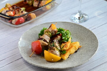 A modern plated meal featuring a juicy grilled chicken skewer with colorful bell peppers and red...