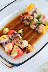Chicken skewers with savory sauce in a glass baking dish, fresh from the oven. A delicious homemade meal scene showcasing rustic cooking and comfort food in a cozy kitchen setting.