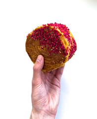 The hand is holding a delicious croissant with raspberry crumbs.