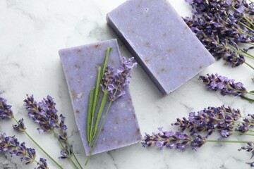 Soap bars and lavender flowers on white marble table, flat lay