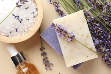 Aromatic soap bars, lavender flowers and cosmetic products on beige background, flat lay