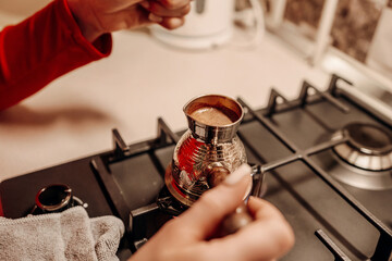 Coffee Brewing Turkey Stovetop: Hands prepare traditional Turkish coffee on a gas stove, kitchen setting.