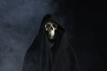 Creepy ghost. Skeleton covered with sheet in smoke on black background