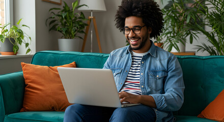 Happy man working from home on laptop smiling successful entrepreneur remote work freelance digital nomad online business technology home office comfort cozy sofa
