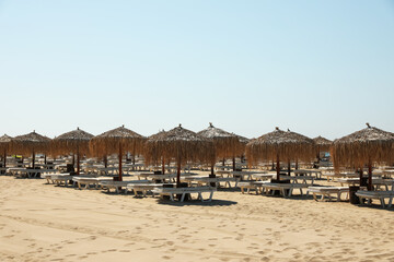 Beautiful straw umbrellas and sunbeds on sandy beach