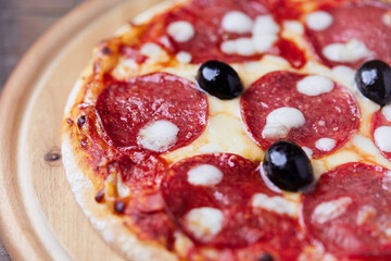 Pizza with salami and mozzarella cheese. Wooden background. Soft focus. Close up.	