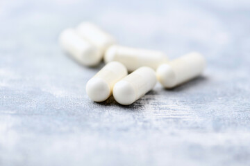 Creatine capsules on bright wooden background. Soft focus. Close up. Copy space.	