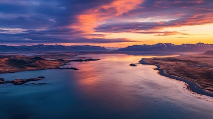 Fototapeta premium Aerial view of Icelandâ€™s stunning landscape, coastal road, mountains, and ocean lit by the warm colors of sunset 