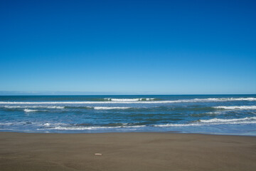 Serene Beach Scene with Gentle Waves and Clear Blue Sky