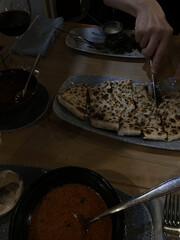 Editorial image of traditional Middle Eastern dinner with flatbread, soup, and red wine