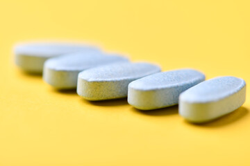 Multivitamin tablets on bright paper background. Close up. Copy space	