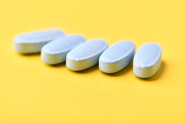 Multivitamin tablets on bright paper background. Close up. Copy space	