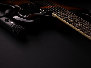 Microphone and electric guitar on a dark background.	