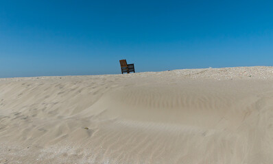 scenic view of a solitary chair on the sand of an off-season beach